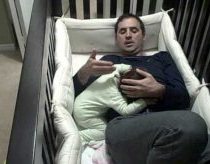 Tėtis įlipa į vaikišką lovelę kad nuramintų verkiantį kūdikį